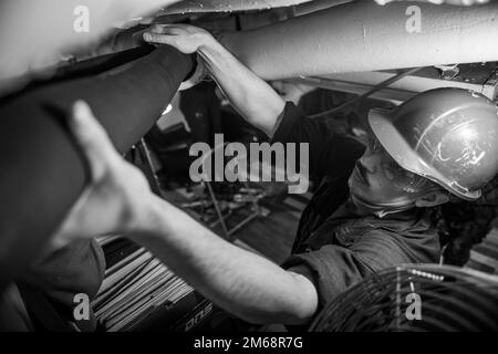 YOKOSUKA, Giappone (19 aprile 2022) – Operations Specialist Seaman Jacob Dess, di West Palm Beach, Fla., test si adatta a un nuovo pezzo di schiuma in ritardo su un tubo a bordo della nave ammiraglia USS Blue Ridge (LCC 19) 7th 2022 aprile 19 a Yokosuka, Giappone. Il ritardo è utilizzato come isolamento termico per tubi e paratie all'interno della nave. Blue Ridge è la più antica nave operativa della Marina militare e, come la 7th Fleet Command ship, lavora attivamente per promuovere le relazioni con alleati e partner nella regione di Indo-Pacifico. Foto Stock