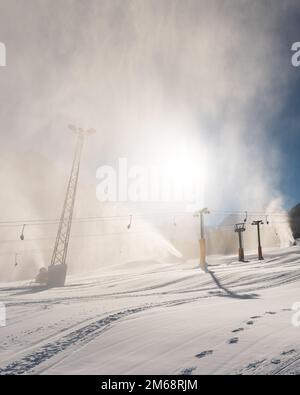 Macchina per innevamento cannone da neve o pistola in azione in una fredda giornata invernale di sole nella località sciistica di Kranjska Gora, Slovenia Foto Stock