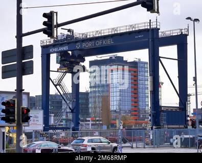 Kiel, Germania - 27.Dicembre 2022: Una grande gru industriale solleva container pesanti con carico al porto di Kiel in condizioni di sole Foto Stock