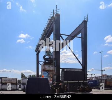 Kiel, Germania - 27.Dicembre 2022: Una grande gru industriale solleva container pesanti con carico al porto di Kiel in condizioni di sole Foto Stock