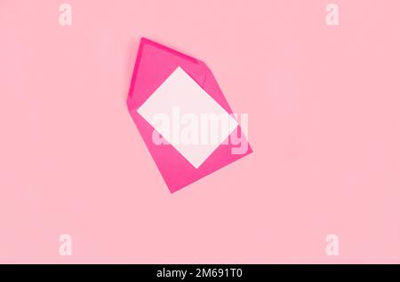 Composizione minima con busta rosa e cartoncino bianco su sfondo rosa. Mockup con busta e scheda vuota. L'appartamento è disposto. Biglietto d'auguri Foto Stock