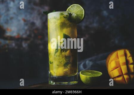 Mango Mojito fatto in casa in un vaso di vetro alto su sfondo scuro, fuoco selettivo Foto Stock