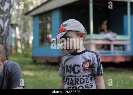 Regione di Chelyabinsk, Russia - 12 luglio 2019. Il ragazzo carino guarda giù nel pensiero. Foto Stock