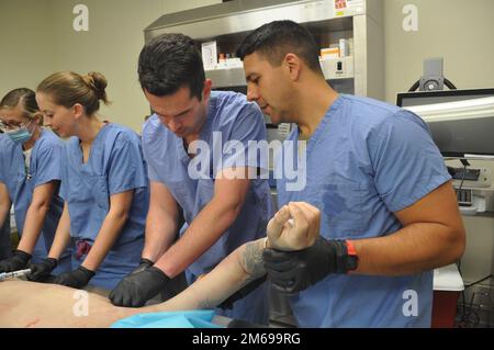 Michael Aguilar ha camminato il programma di residenza della medicina della famiglia laureando il captano residente Matthew Stewart attraverso un inserimento del tubo toracico su un cadaver come parte dell'esperienza di residenza della medicina della famiglia (FMRx), aprile 20. Nella foto, da sinistra a destra, si trovano anche il Capo residente, il Capo Shelby Sheider e il Capo Victoria Hall. Foto Stock