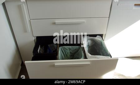 Tre contenitori per rifiuti per tipi di rifiuti separati in una stanza da cucina Foto Stock