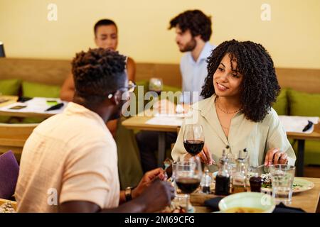 Una felice coppia multiculturale sta cenando in un ristorante. Sono in una data o festa di anniversario. Foto Stock