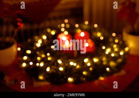 Wreath di Natale con luci fata e candele brucianti di Avvento sfondo sfocato Foto Stock
