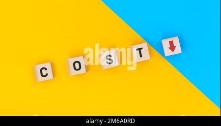 Cubetti di legno di blocco che capovolgono il costo a giù. Riduzione dei costi per maggiori concept di profitto Foto Stock