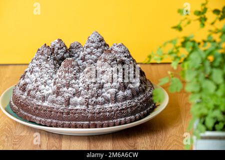 Una torta natalizia al cioccolato. La torta viene fatta usando una teglia per formare la pastella per torte nelle forme dell'albero. Una spruzzata di zucchero a velo lo supera Foto Stock