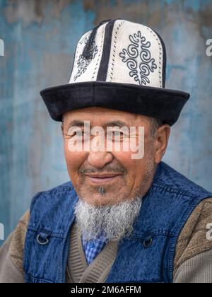 Murghab, Gorno-Badakshan, Tagikistan - 08 27 2019 : Ritratto in primo piano dell'uomo anziano che indossa il tradizionale cappello kalpak kirghiso sul mercato lungo l'autostrada Pamir Foto Stock