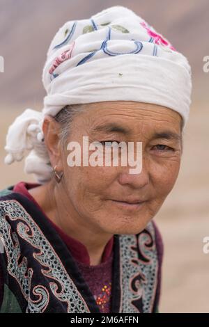 Distretto di Murghab, Gorno-Badakshan, Tagikistan : 08 27 2019 : Ritratto della vecchia donna kirghise con occhi blu e sciarpa bianca lungo la Pamir Highway Foto Stock