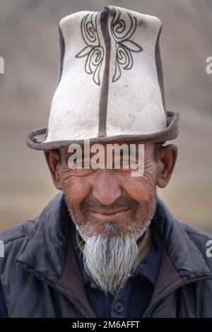 Distretto di Murghab, Gorno-Badakshan, Tagikistan : 08 27 2019 : Ritratto dell'uomo kirghiso che indossa il tradizionale cappello in feltro kalpak lungo l'autostrada Pamir Foto Stock