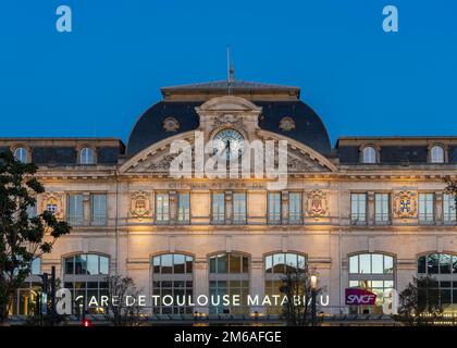 Tolosa, Francia - 12 21 2022 : Vista della facciata della stazione ferroviaria Matabiau illuminata dopo il tramonto Foto Stock