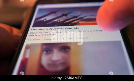 Scorrere le notizie della BBC dall'Ucraina su un telefono cellulare. Faccia figlio. Foto Stock