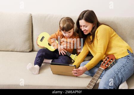 Mamma e figlia imparano a giocare l'ukulele Foto Stock