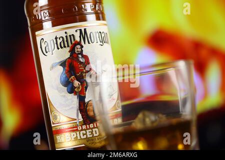 KIEV, UCRAINA - 4 MAGGIO 2022 Capitano Morgan bottiglia di alcol originale su tavolo di legno con camino rosso sullo sfondo. Produzione di alcool Elite Foto Stock