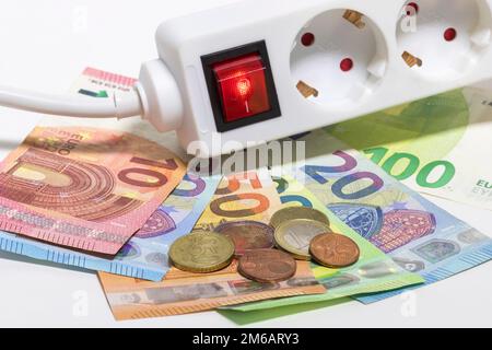 Striscia di prese elettriche commutabili, banconote in euro, monete in euro, costi energetici Symbol, costi dell'elettricità, risparmio energetico Foto Stock