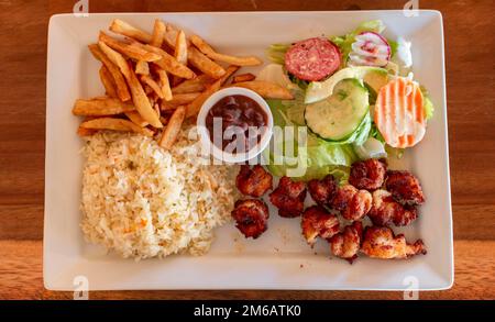 Piatto di gamberetti impanati con riso e insalata sul tavolo di legno. Vista dall'alto di gamberi impanati con patatine fritte e insalata servita su un tavolo di legno. Foto Stock