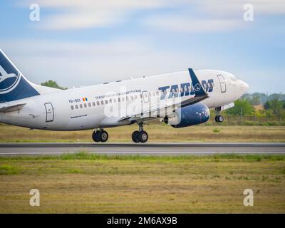 Bucarest, Romania - Agosto 2022: Un velivolo TAROM BOEING 737-700 che vola contro il cielo blu chiaro. L'aereo parte dall'aeroporto internazionale Henry Coanda ai Foto Stock