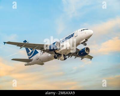 Bucarest, Romania - 2022 agosto: Aereo TAROM Airbus A318 che vola contro il cielo al tramonto. L'aereo parte dall'aeroporto internazionale Henri Coanda Foto Stock