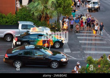 Auto e taxi con pubblicità colorata in un incrocio trafficato, pedoni che attraversano le traversate zebra, vista dall'alto, crepuscolo su Las Vegas Foto Stock