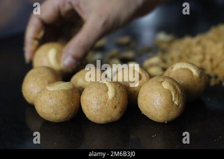 Preparazione di moong dal laddu a forma di palla con mano. È un dolce indiano ricco di proteine, fatto di lenticchie, mandorle e gelificazione come dolcificante. Scatto wi Foto Stock