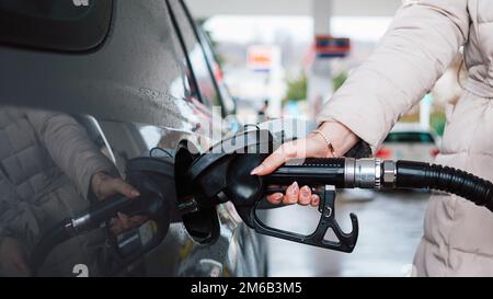 Donna che pompa benzina in auto alla stazione di benzina. Concetto di aumento del prezzo della benzina o della benzina. Foto Stock