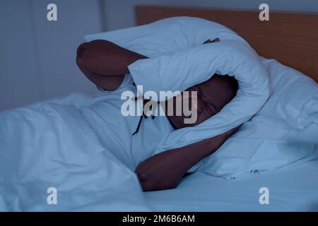 Uomo che si copre la testa con un cuscino nel letto, vista dall'alto.  Problema di insonnia Foto stock - Alamy