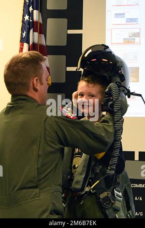 STATI UNITI Kevin 'Sajaca' Donovan, un pilota con il 131st Fighter Squadron, aiuta un membro del Southwick Massachusetts Boy Scout Troop 338 e i membri della famiglia di accompagnamento a provare l'attrezzatura di volo durante un tour della 104th Fighter Wing 22 aprile 2022, presso la base della Guardia Nazionale aerea di Barnes, Massachusetts. I tour offrono l'opportunità di rafforzare le relazioni, mettendo in evidenza la missione unica e le abilità degli anni '104FW per la comunità e i partner della comunità circostante. Foto Stock