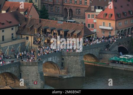 Vista sul fiume meno e sul vecchio ponte principale con persone che bevono vino da Würzburg in Germania. Foto Stock