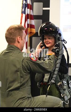 STATI UNITI Kevin 'Sajaca' Donovan, un pilota con il 131st Fighter Squadron, aiuta un membro del Southwick Massachusetts Boy Scout Troop 338 e i membri della famiglia di accompagnamento a provare l'attrezzatura di volo durante un tour della 104th Fighter Wing 22 aprile 2022, presso la base della Guardia Nazionale aerea di Barnes, Massachusetts. I tour offrono l'opportunità di rafforzare le relazioni, mettendo in evidenza la missione unica e le abilità degli anni '104FW per la comunità e i partner della comunità circostante. Foto Stock