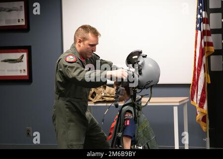 STATI UNITI Kevin 'Sajaca' Donovan, un pilota con il 131st Fighter Squadron, aiuta un membro del Southwick Massachusetts Boy Scout Troop 338 e i membri della famiglia di accompagnamento a provare l'attrezzatura di volo durante un tour della 104th Fighter Wing 22 aprile 2022, presso la base della Guardia Nazionale aerea di Barnes, Massachusetts. I tour offrono l'opportunità di rafforzare le relazioni, mettendo in evidenza la missione unica e le abilità degli anni '104FW per la comunità e i partner della comunità circostante. Foto Stock