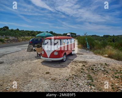 Primosten, Croazia - 06 27 2015: Vecchio vintage VW vetrata micro bus in rosso e bianco sul lato della strada sulla costa mediterranea Foto Stock