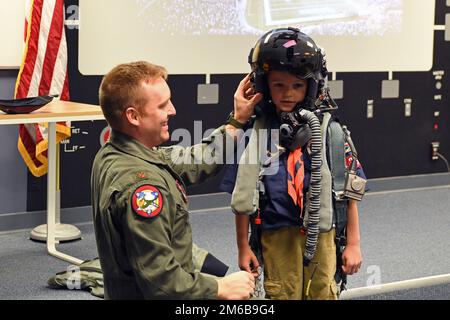 STATI UNITI Kevin 'Sajaca' Donovan, un pilota con il 131st Fighter Squadron, aiuta un membro della squadra Southwick Massachusetts Boy Scout 338 e i membri della famiglia di accompagnamento a provare l'attrezzatura di volo durante un tour della 104th Fighter Wing 22 aprile 2022, presso la base della Guardia Nazionale dell'aria di Barnes, Massachusetts. I tour offrono l'opportunità di rafforzare le relazioni, mettendo in evidenza la missione unica e le abilità degli anni '104FW per la comunità e i partner della comunità circostante. Foto Stock