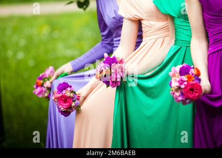 Bridesmaids in abiti colorati con bouquet di f Foto Stock