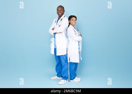 Uomo e donna doc africano-americana maturi in posa con braccia piegate, medici esperti che indossano camici da laboratorio Foto Stock