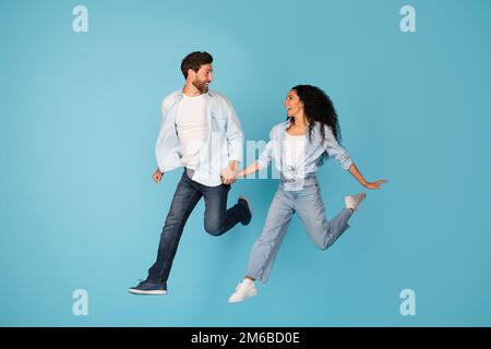 Sorridente eccitato sorpreso giovane coppia europea in esecuzione, saltando, congelare in aria per copiare spazio Foto Stock