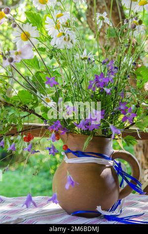 Brocca con un bouquet di fiori d'estate su un tavolo in giardino Foto Stock