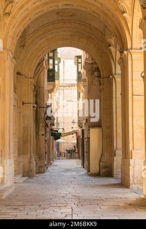 Strada maltese a la Valletta con archi in pietra calcarea dorata splendidamente intagliati Foto Stock