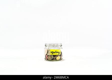 Risparmio di alta qualità primo piano vaso di vetro con monete, scatola di denaro, Penny o banca piggy. Risparmio denaro moneta. Penny Bank su sfondo bianco. Adesivo giallo Foto Stock