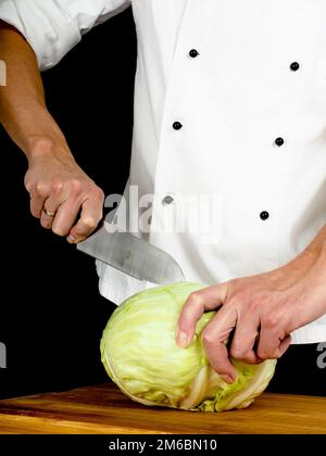 Chef professionista che tiene un coltello da cucina affilato e cavolo Foto Stock