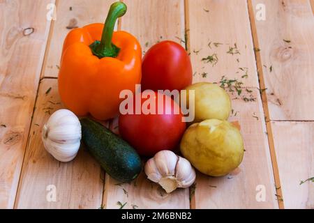 Patate, pomodori, peperoni, cetrioli e aglio su una superficie di legno Foto Stock