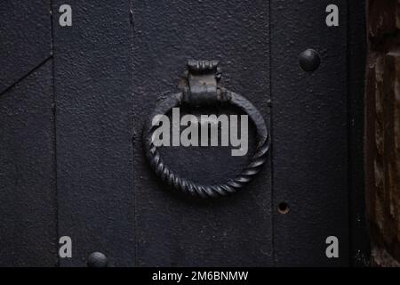 maniglia forgiata rotonda su una vecchia porta in ferro nero primo piano Foto Stock