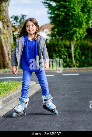 Bambina facendo andare in rollerblade in strada Foto Stock