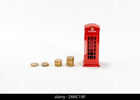 Cabina telefonica rossa con monete impilate cassetta di denaro londra, penny o piggy banca su sfondo bianco. Risparmio di denaro idea foto hd. Risparmio di denaro. Foto Stock