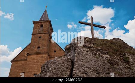 Vista su una chiesa e una croce di fronte ad un meraviglioso cielo velato - leggermente dai toni seppia Foto Stock