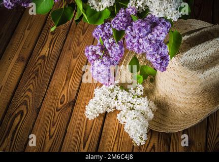 Still-life con un mazzo di lillà e un cappello di paglia, close-up Foto Stock