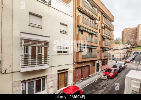 Facciate di case residenziali di tre e quattro altezze in una strada stretta con auto parcheggiate Foto Stock