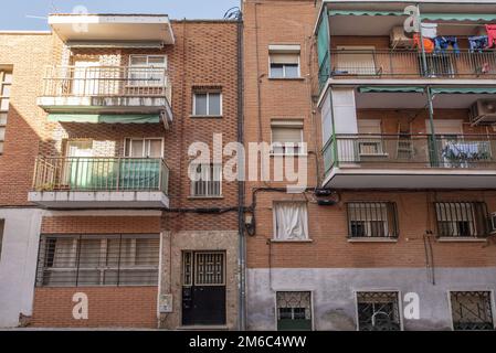 Facciate di case residenziali di tre e quattro altezze in una strada stretta con balconi e seminterrati con bar Foto Stock