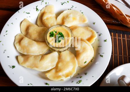 Ucraini e russi vareniki piatto con purè di patate e la panna acida e salsa di funghi sulla piastra bianca. Close up. Foto Stock